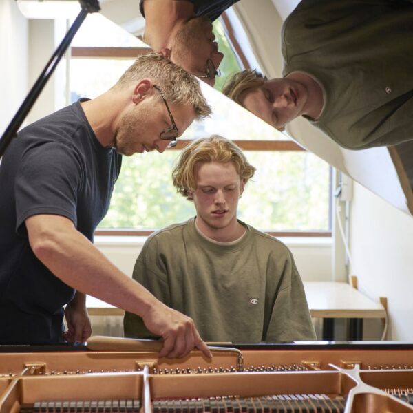 Een student die uitleg krijgt over het stemmen van de piano