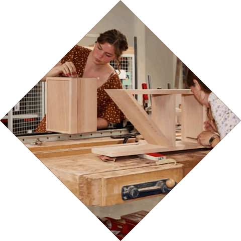 2 studenten zijn aan het werk aan hun houten werkstuk