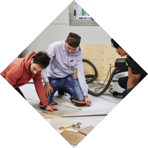 Een aantal studenten discussieren hoe ze het beste laminaat kunnen leggen