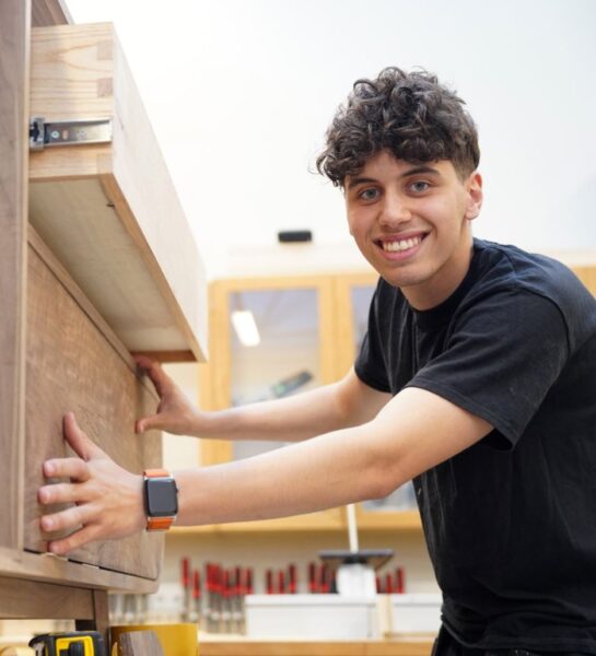 Student is zijn kast aan het stellen en lacht in de camera