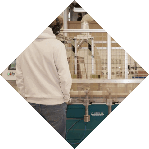 Student staat bij een machine en heeft gehoorbescherming op