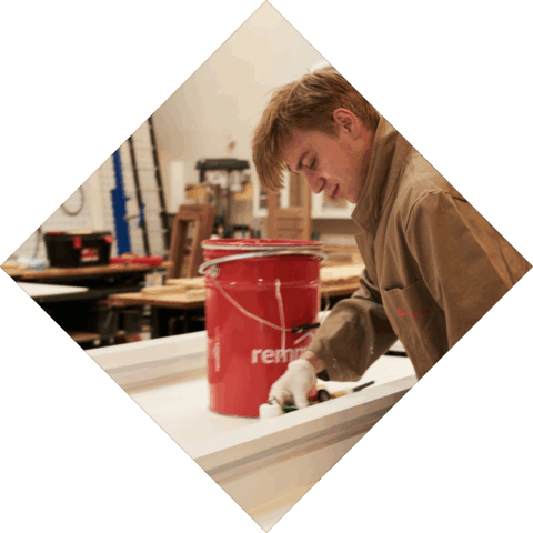 Student is een kozijn aan het aflakken