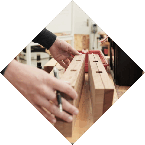 Student heeft een potlood in de hand en is 2 planken hout aan het afmeten