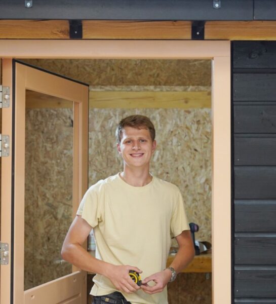 Student is met een rolmaat aan het meten en kijkt in de camera